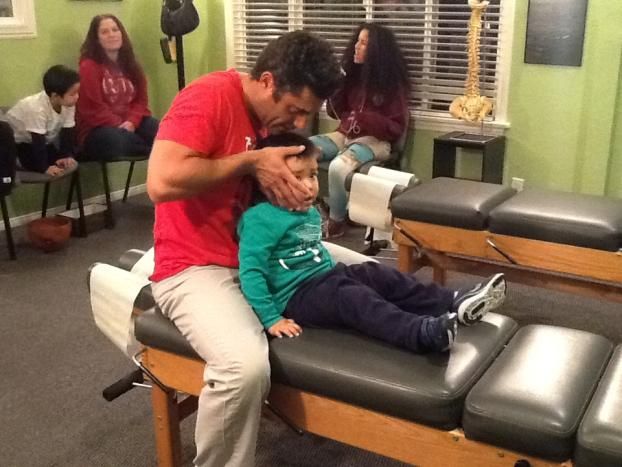 Dr. Biscotti of South Bay Family Chiropractic is performing pediatric chiropractic care in this child chiropractor adjustment photo.
